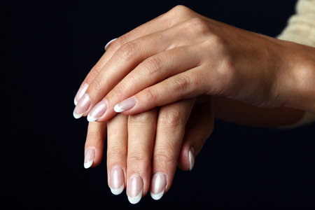 Beautiful woman hand with french manicure, isolated on black backgroundの写真素材