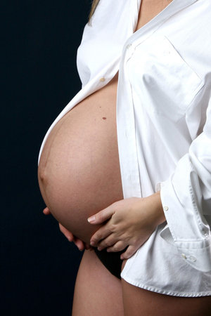 Young pregnant woman in white shirt on dark background