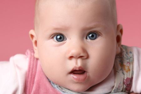 Little cute surprised child. Close-up portrait on pink backgroundの写真素材