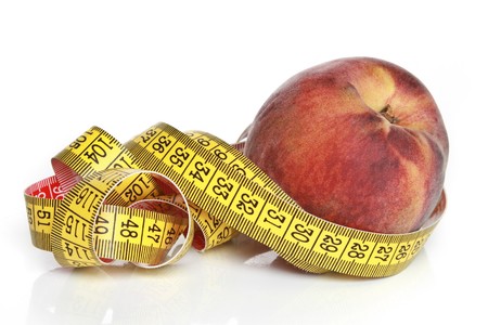 Yellow measuring tape with peach on a white backgroundの写真素材