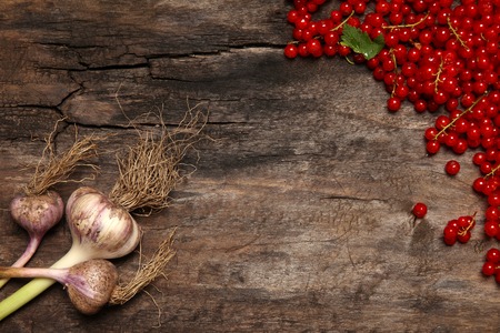Fresh red currant berries and garlic on old wooden backgroundの写真素材