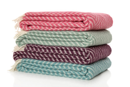 A stack of folded blankets lying on top of each other on a white backgroundの写真素材