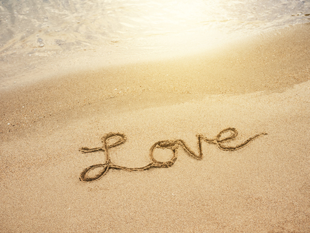 Love lettering message written on Sand Beach background with sunriseの写真素材