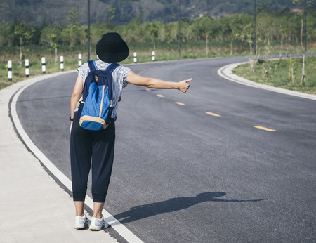 Teenager with Backpack Hitch Hiking on Roadの写真素材