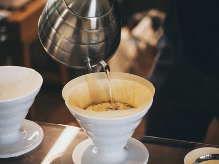 Hand drip coffee Barista pouring water on coffee ground with filterの写真素材