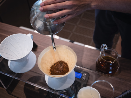 Hand drip coffee Barista pouring water on coffee ground with filterの写真素材