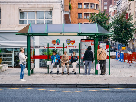 BILBAO, SPAIN - OCT 19, 2018 :  People waiting bus at Bus stop. Woman wear mask virus protection in...