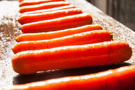 Fresh carrots on black wood board in bright sun lightの写真素材