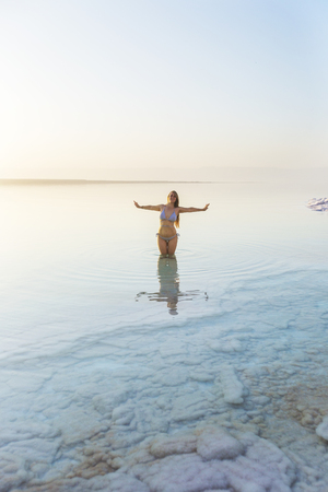 Woman is standing in salty water of a Dead Seaの写真素材