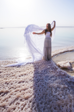 Blonde young woman in a long skirt on the shore of the dead sea. Jordanの写真素材