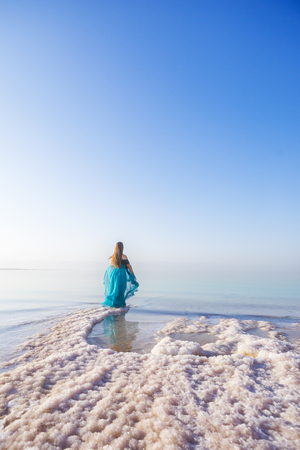 Blonde young woman in a blue dress on the shore of the dead sea. Jordanの写真素材