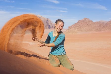 young woman with a smile sprinkled sand in the desertの写真素材