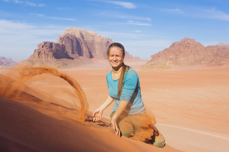 young woman with a smile sprinkled sand in the desertの写真素材