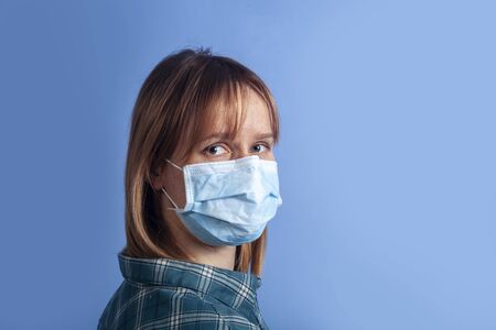 woman wearing facial mask for protection from air pollution or virus epidemic on blue backgroundの写真素材