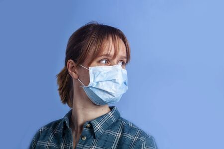 woman wearing facial mask for protection from air pollution or virus epidemic on blue backgroundの写真素材