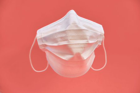 Face mask isolated on light red background