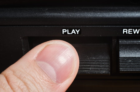 Finger pressing the play button on cassette player