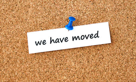 We have moved. Text written on a piece of paper or note, cork board background.の写真素材
