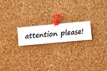 Attention please. Text written on a piece of paper or note, cork board background.の写真素材