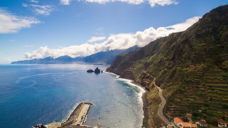 Coastal road with steep coast and beautiful blue ocean and sky, Madeira, Portugalの写真素材