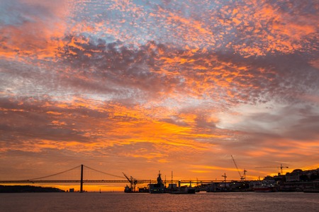 Incredible Golden sunset over the river Tagus, Bridge April 25 and the port Lisbon, Portugal.の写真素材
