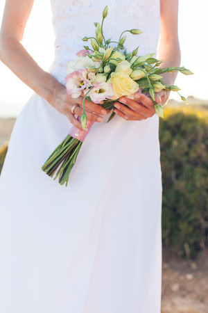 The bride in a white dress holding beautiful wedding bouquet of rosesの写真素材