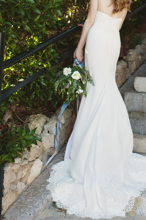 Bride in a beautiful long white wedding dress holding  bouquet of flowersの写真素材