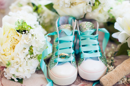 Wedding rings, flowers and childrens shoes compositionの写真素材