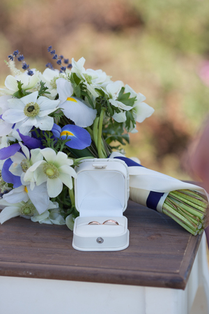 Wedding rings and white blue flower bouquetの写真素材