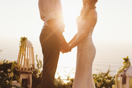 The bride and groom on the background of the Ocean during sunsetの写真素材