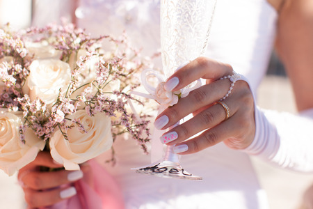 Bride holding a glass of champagne and wedding bouquetの写真素材