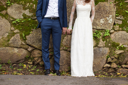 A pair of newlyweds in an old stone wall close-upの写真素材