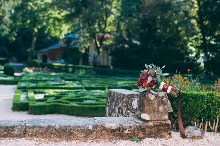 Red and green wedding bouquet on a background of an old garden close-upの写真素材