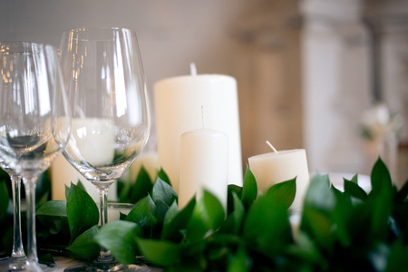 Glasses, candles and Fresh Greens on the wedding table close-upの写真素材