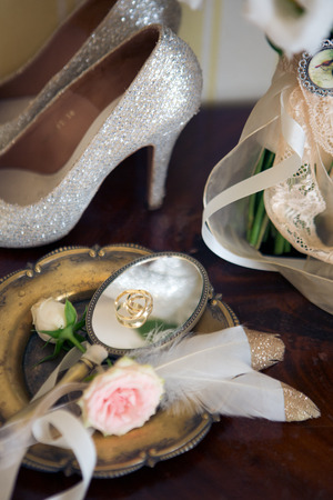 Wedding decoration: shoes, rings and bouquet on a tableの写真素材