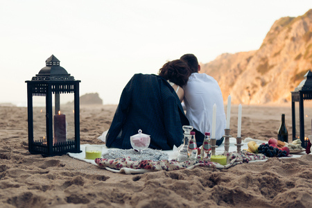 Loving couple on a romantic date at the beach during sunsetの写真素材