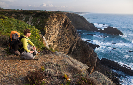 Tourist with backpack on the edge of a beautiful cliff near the ocean Portugal Algarveの写真素材