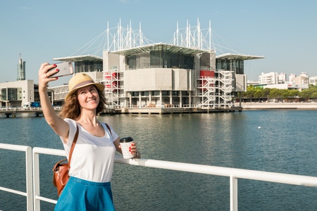 Attractive young woman make photo near Lisbon Oceanarium near river Tagusの写真素材