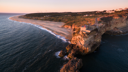 Aerial view of ocean, north Beach and Nazare lighthouse at sunset, Portugalの写真素材