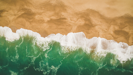 Beautiful ocean waves and splashes on a sandy beach in Nazar , Portugal. Aerial viewの写真素材