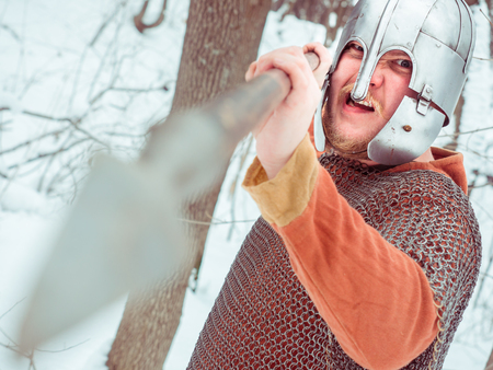 Medieval Irish warrior in chain mail and helmet holds a spear in the winter forestの写真素材