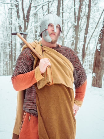 Medieval Irish warrior in mail and helmet holds a hammer in the winter forestの写真素材