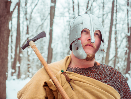 Medieval Irish warrior in mail and helmet holds a hammer in the winter forestの写真素材