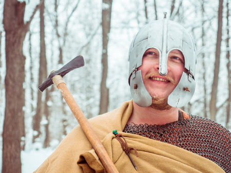 Medieval Irish warrior in mail and helmet holds a hammer in the winter forestの写真素材