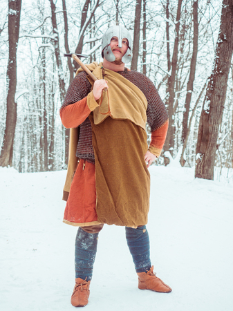 Medieval Irish warrior in mail and helmet holds a hammer in the winter forestの写真素材