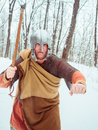 Medieval Irish warrior in mail and helmet holds a hammer in the winter forestの写真素材