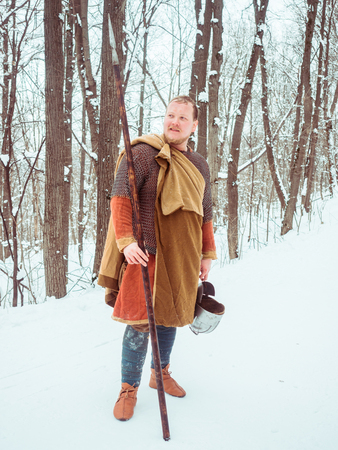 Medieval Irish warrior in chain mail and helmet holds a spear in the winter forestの写真素材