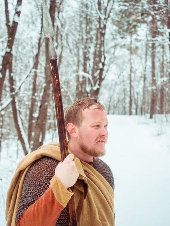Medieval Irish warrior in chain mail and helmet holds a spear in the winter forestの写真素材
