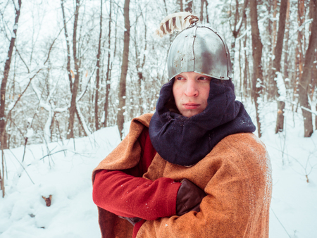 Frankish warrior in historical costume with helmet in winter forestの写真素材