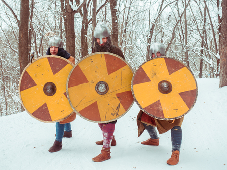 A group of armed medieval warriors are guarded with shields, swords, spears in the winter forestの写真素材